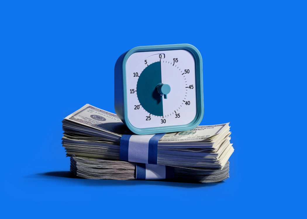 a kitchen timer sits on top of a pile of dollar bills, implying a quick and smooth process